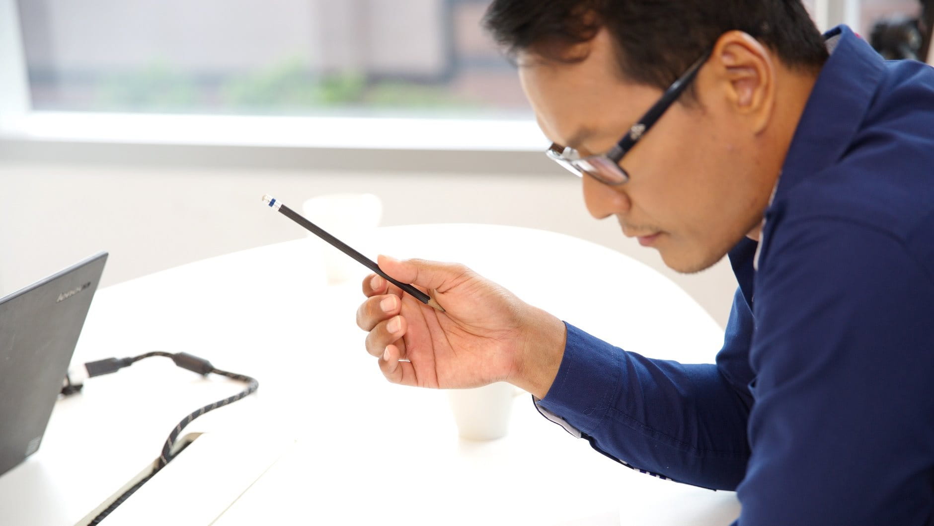 Asian worker with glasses leaning over a working document holding a pencil